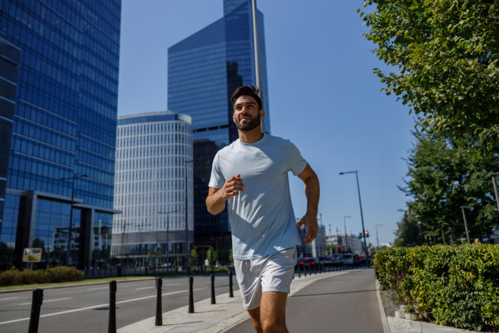 Male athlete runner training at city street on background of skyscrapers. Healthy lifestyle concept