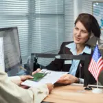 Kobieta składająca formularz wniosku wizowego przy okienku w urzędzie imigracyjnym