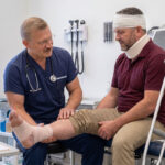 Dr Dariusz Nasiek bada nogę pacjenta po wypadku przy pracy
