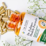 Bottle of Dr. Fulmes Health Formula dietary supplement with scattered capsules and baby's breath sprigs