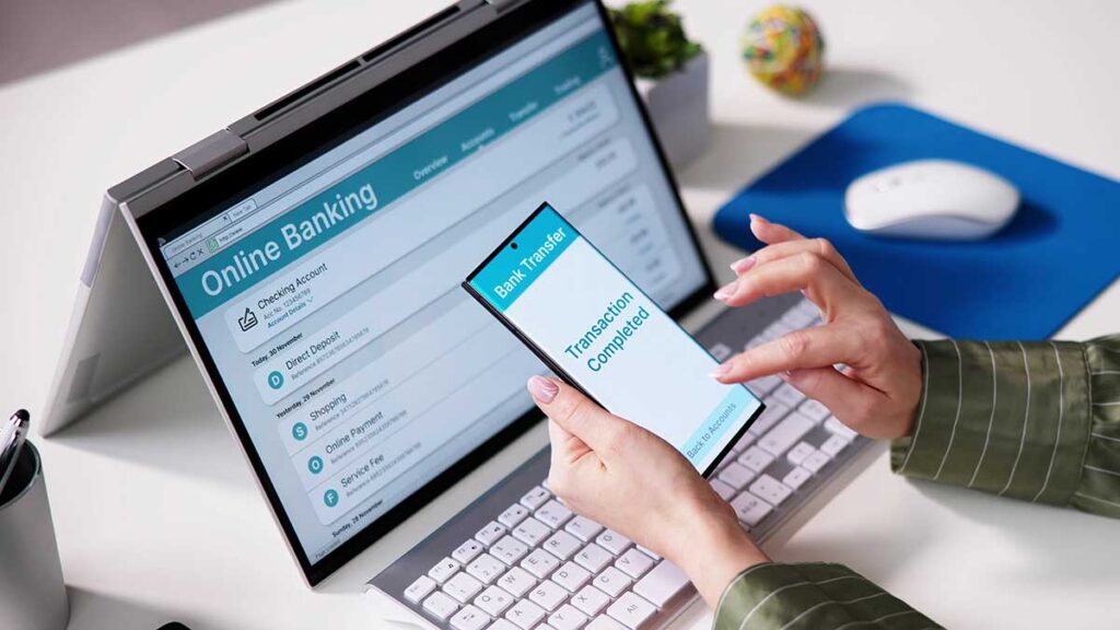 Laptop and phone with a banking app – sending money to Poland