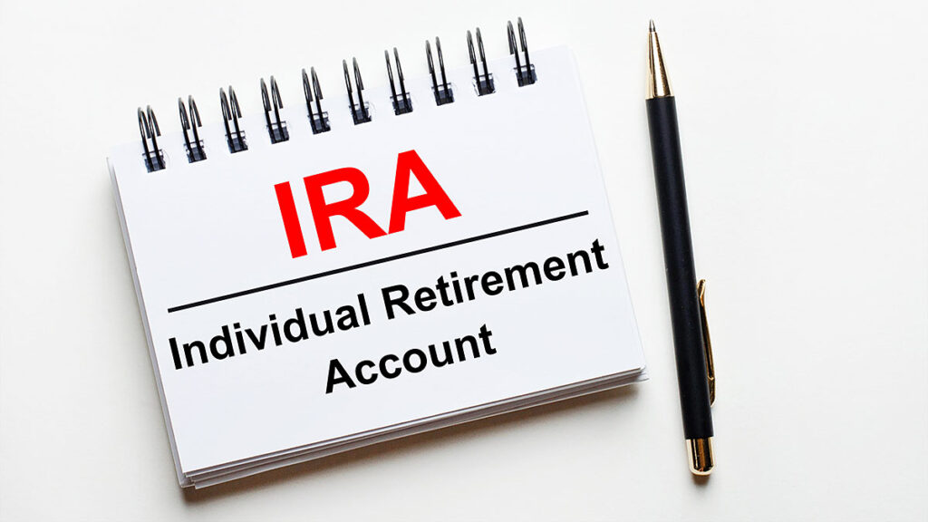 Notebook reading IRA – Individual Retirement Account with a pen – taking money out of an IRA