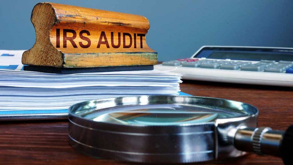 IRS Audit stamp, documents and a magnifying glass – how to avoid an IRS audit