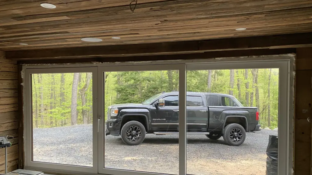 Large sliding glass patio doors in a house with wood-paneled walls and ceiling