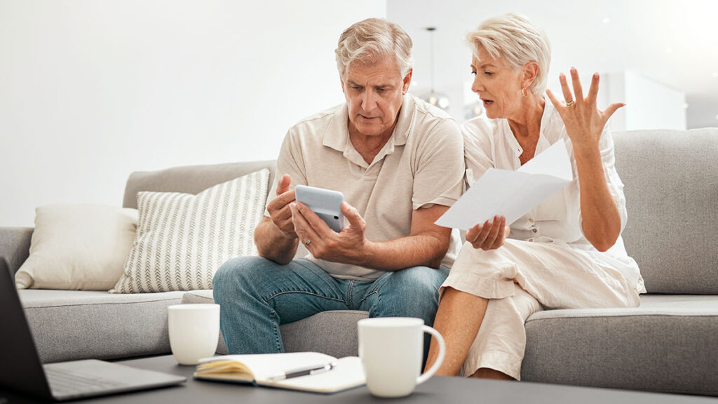 Senior couple reviewing papers on a sofa – divorce in the U.S. and Social Security